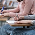 Najtrudniejsze typy zadań z chemii rozszerzonej. Jak sobie z nimi poradzić? Young female university students concentrate on doing examinatio